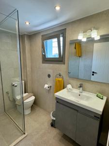 a bathroom with a sink and a toilet and a mirror at Betty's Beach House - by the Sea in Kámpos