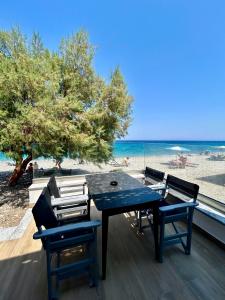 a table and chairs on a deck with the beach at Betty's Beach House - by the Sea in Kámpos