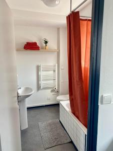 a bathroom with an orange shower curtain and a sink at L'écrin du général in Armentières
