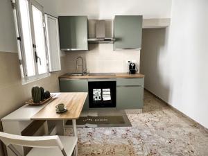 une cuisine avec des armoires vertes, une table et un évier dans l'établissement Lucky Corner - Elegant Stay, à Tarente