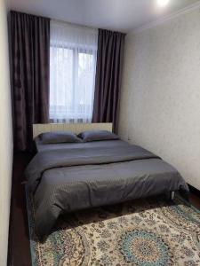 a bedroom with a bed with a window and a rug at Уютная квартира , с удобствами in Taraz