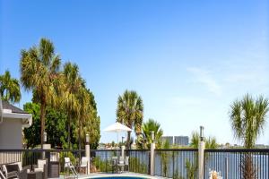 a pool with chairs and a fence with palm trees at Holiday Inn Express Hotel & Suites Tampa-Rocky Point Island by IHG in Tampa
