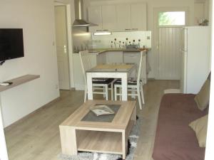 a living room with a table and a kitchen at L'Oliveraie in La Motte-dʼAigues