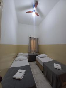 a room with three beds and a ceiling fan at Hotel Central in Araçatuba