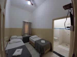 a hospital room with three beds and a shower at Hotel Central in Araçatuba