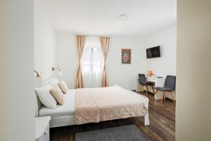 a white bedroom with a bed and a desk at Green lakes house in Plitvička Jezera