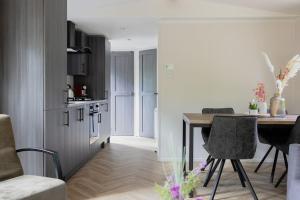 a living room with a table and a kitchen at Schitterend chalet in het bos in Doornspijk