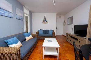 Una sala de estar con un sofá azul y un televisor. en Casa Playa María, en Agaete