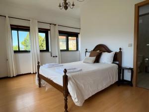 ein Schlafzimmer mit einem Bett mit weißen Laken und Fenstern in der Unterkunft Quinta da Graça Casa do Artista in Resende