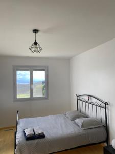 a white bedroom with a bed with a window at Vue panoramique & jacuzzi privé in Saint-Hilaire