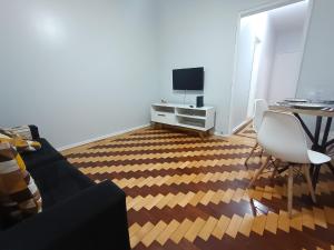 a living room with a couch and a desk with a television at Na Cidade Baixa, perto de tudo - UFRGS, Santa Casa, Parques, Orla in Porto Alegre +34 photos