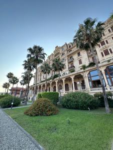 a large building with palm trees in front of it at Appartamento Malibù Miramare in Genoa