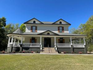 a large white house with a porch on a lawn at Victorian mini mansion near Lake Greenwood in Cross Hill