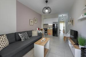 a living room with a gray couch and a kitchen at City Center Apartment in Ioannina