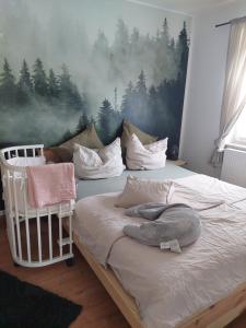 a bedroom with a bed with a forest mural on the wall at Ferienwohnung Schwingestraße in Dinghorn +3 photos