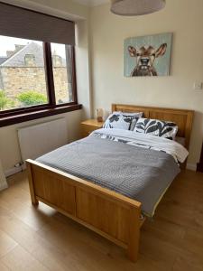 a bedroom with a bed with a cow picture on the wall at My Alba Home in Fife