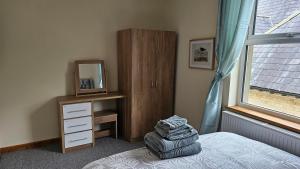 a bedroom with a bed and a dresser and a mirror at The Apartment at Brook House in Llanberis +4 photos