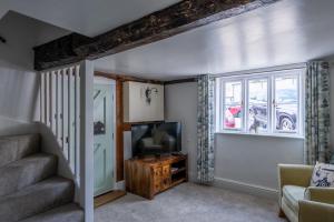 a living room with a staircase and a television at Grade 2 Cottage 1 bedroom, Ludlow centre in Ludlow