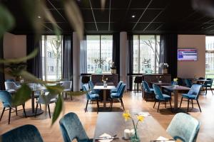 a restaurant with tables and chairs and windows at Das Steinmüller Hotel in Gummersbach