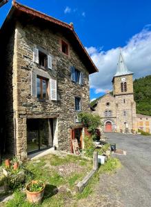 an old stone building with a church in the background at Chez la ptite famille in Saint-Didier-sur-Doulon