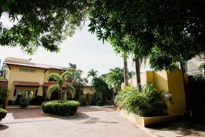 a yellow building with palm trees and a driveway at Porto Bello Hotel Boutique in Puerto Colombia