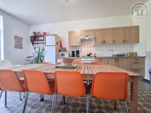 a kitchen with a wooden table and orange chairs at Villa spacieuse avec jardin, terrasse, et équipements complets à Baives, proche Belgique et Val Joly - FR-1-510-218 in Baives