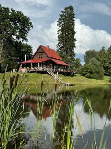 a house with a red roof next to a lake at Brīvdienu māja Straumēni in Pāle