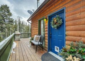 a wooden house with a blue door and a chair on a deck at Pinetop Cabin Hot Tub BBQ Arcade Scenic Escape in Florissant +52 photos