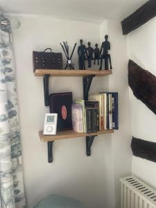 a shelf with books and figurines on a wall at Grade 2 Cottage 1 bedroom, Ludlow centre in Ludlow