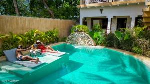 two people sitting on lounge chairs next to a swimming pool at Chikachika Beach B&B in Nungwi