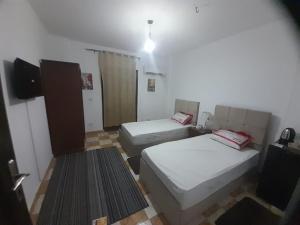 a small room with two beds and a television at Double room in Villa Narges New Cairo in Cairo