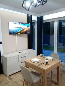 Un comedor con una mesa y un televisor en la pared. en Kaszmirowy zakątek, en Augustów