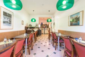 una sala da pranzo con tavoli, sedie e luci verdi di Pension Prenzlberg a Berlino