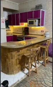 une cuisine avec un comptoir en bois et des armoires violettes dans l'établissement شاليه للإيجار في راس سدر جولدن بيتش2, à Raʼs Matarma