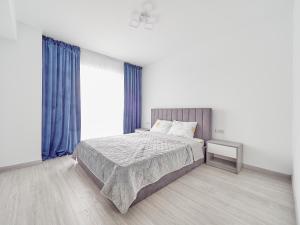 une chambre avec un grand lit avec des rideaux bleus dans l'établissement Decebal Residence Craiova, à Craiova