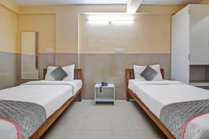 a room with two beds and a table in it at Townhouse Empire Executive in Pune