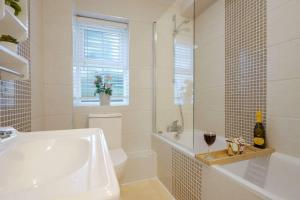 a white bathroom with a tub and a toilet and a glass of wine at Stylish Apartment - Central Location - Free Parking, Self-Check-In, Fast Wifi and Smart TV by Yoko Property in Northampton +14 photos