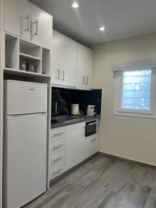 a kitchen with white cabinets and a white refrigerator at Serenity in Rodhodháfni