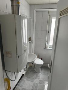 a white bathroom with a toilet and a window at Comfort Apartments Heilbronn in Heilbronn