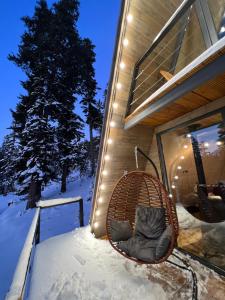 una sedia di vimini seduta fuori da una casa nella neve di Bakhmaro A-frame a Chʼkhakoura Altre 17 foto