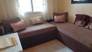 a couch with pillows on it in a living room at Sweet home in Dar Bouazza +1 photo
