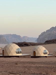 two domes in a desert with mountains in the background at Royal Dunes Camp in Wadi Rum
