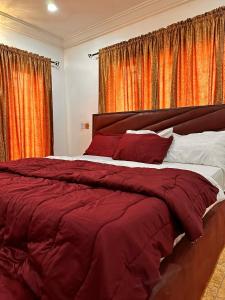 a bedroom with a large bed with red sheets at Savannah Homes in Abuja