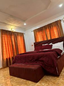 a bedroom with a large bed with red curtains at Savannah Homes in Abuja