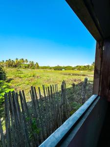 a wooden fence with a field in the background at Refúgio CAJUÍ in Barreirinhas