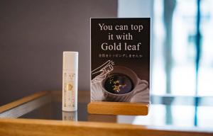 une bouteille de feuille d'or à côté d'un livre sur une table dans l'établissement Hotel Resol Trinity Kanazawa, à Kanazawa