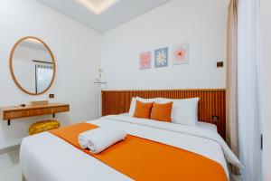 a bedroom with a large bed with an orange blanket at Swaripuna Villa by Nandara Hospitality in Salakan +9 photos