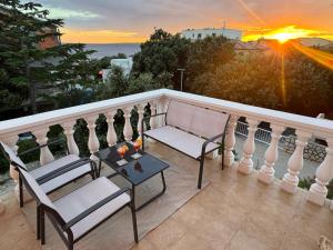 a balcony with two chairs and a table and the sunset at Villa INFINITY in Mandre