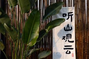 a banner hanging on a bamboo wall with a plant at 青城山泉青小院温泉中式民宿 in Taiping