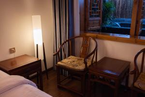 a room with a bed and two chairs and a window at 青城山泉青小院温泉中式民宿 in Taiping